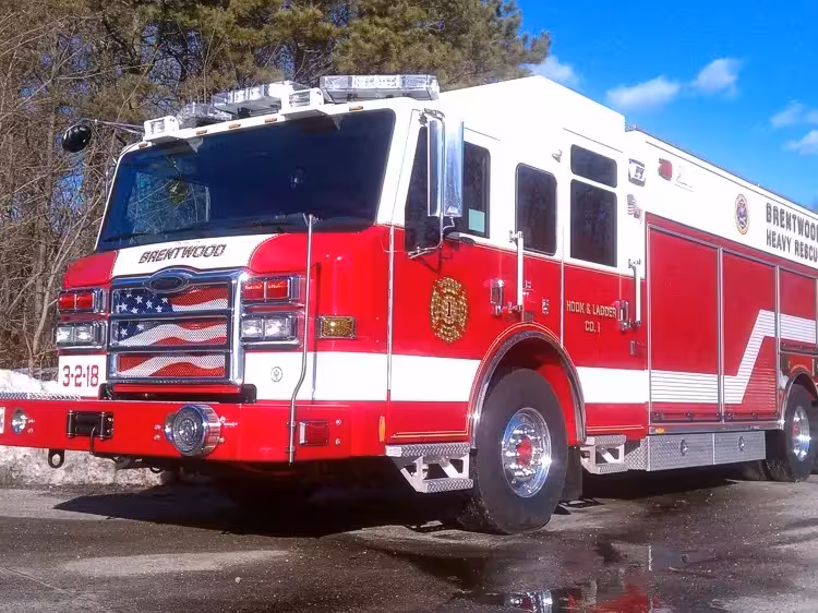 Front left exterior view of a heavy rescue truck with chrome bumper, crew cab, and long side compartments.
