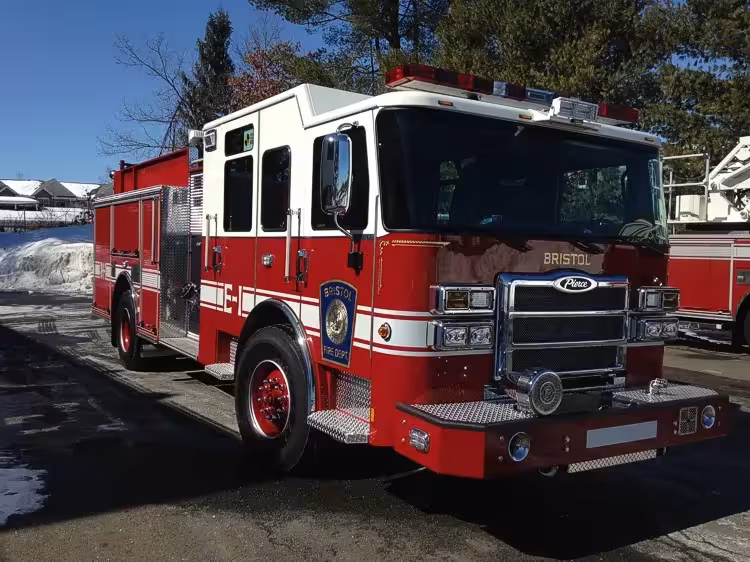 Front-right exterior view of a pumper with enclosed cab, side pump panel section, and body compartments.
