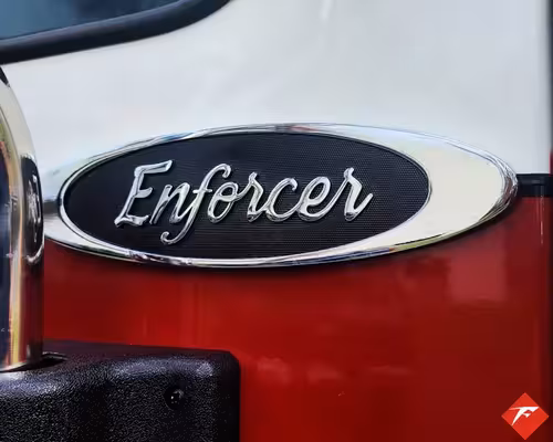 Body badge close-up showing Enforcer emblem on red panel