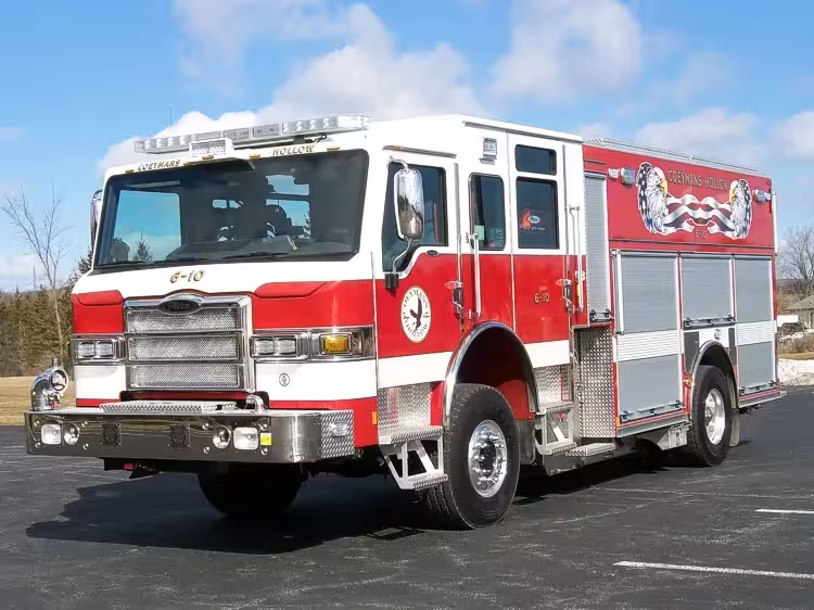 Front-right exterior view of a rescue pumper with enclosed cab, side compartments, and wheel/tire area.
