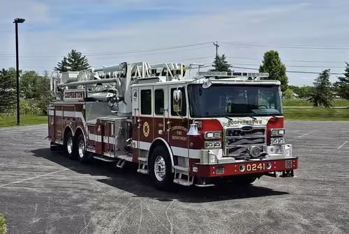 Front-left exterior view showing cab corner and aerial ladder over body