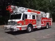 Tower ladder front-left exterior view showing enclosed cab and ladder bed