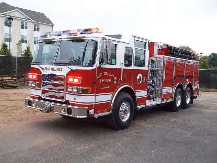 Front left exterior view of the tanker-pumper with triple rear axle, roof lights, and pump panel area visible.