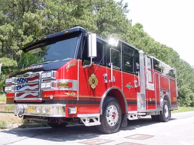 Front left exterior view showing the chrome bumper, flag-style grille, and side compartment body.