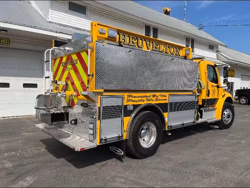 Rear-left exterior view showing chevron striping, rear dump, and side compartments