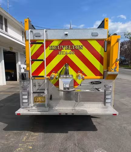 Rear view showing chevron striping, ladder, and rear discharge hardware
