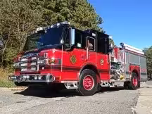 Wide front-left view of the pumper parked roadside with full side body visible.