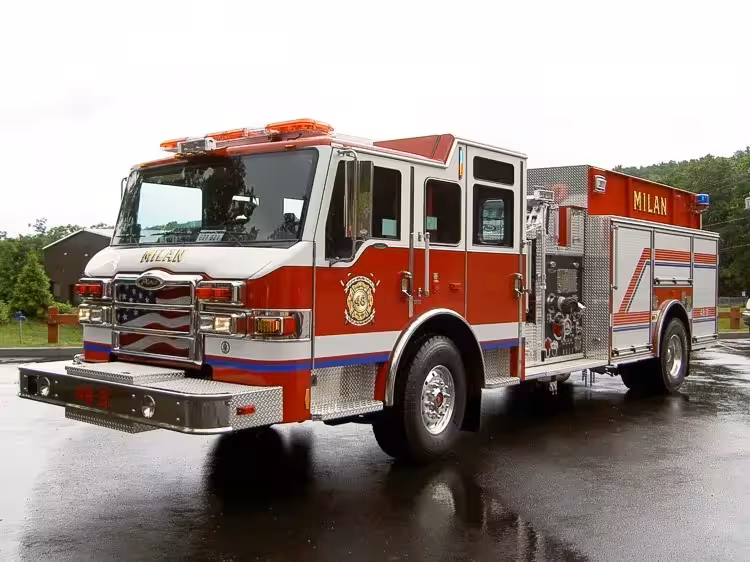 Pumper front-left exterior view on wet pavement showing cab and side compartments
