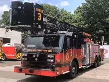 Pierce Ascendant tower ladder front-left view showing bucket, aerial sections, and side compartments