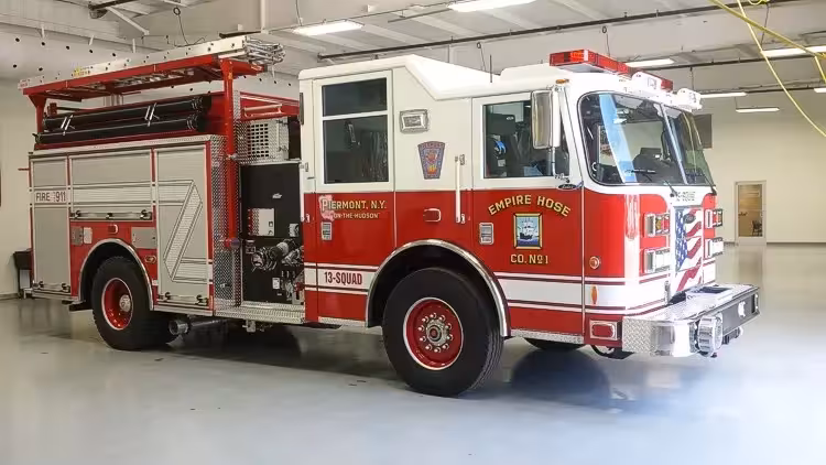 Front-right exterior view of a squad pumper showing the cab, side pump panel area, and rear body compartments.