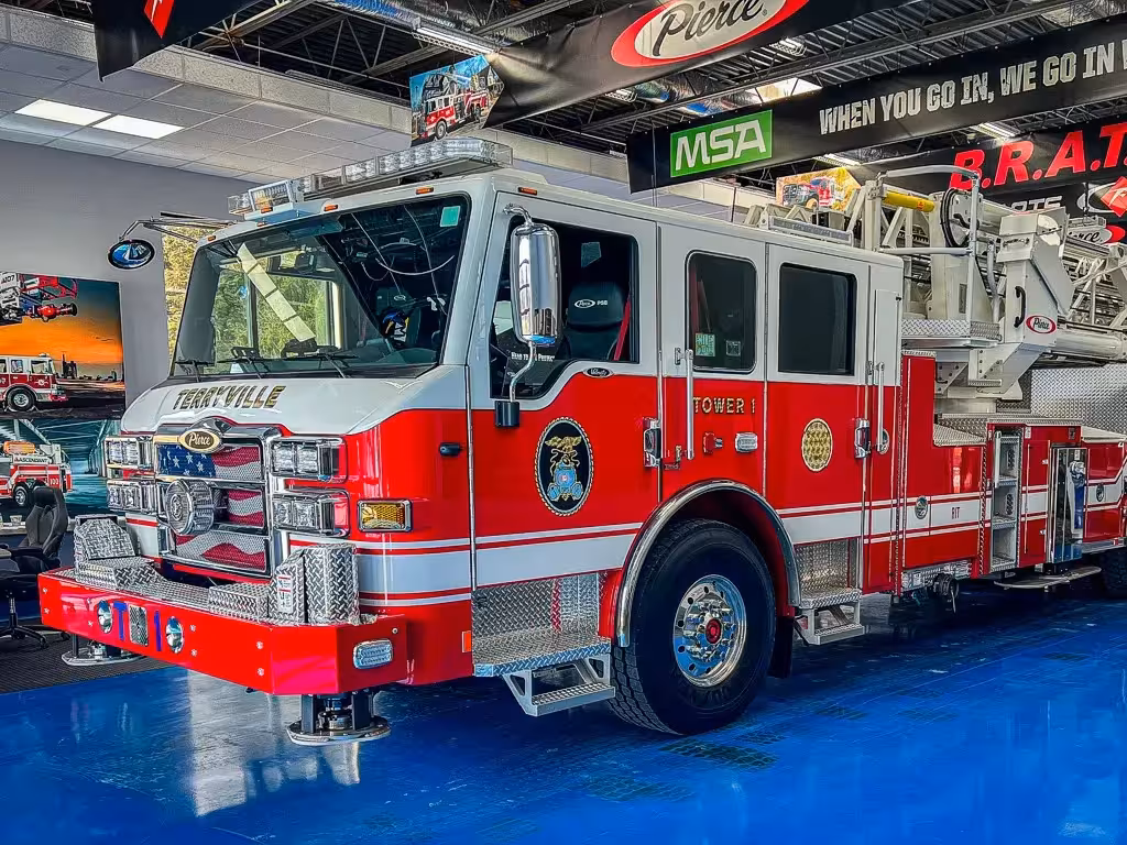 Tower ladder front-left exterior view showing enclosed cab and aerial device above