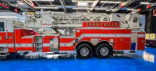 Officer-side full profile view showing side body panels and aerial ladder bed