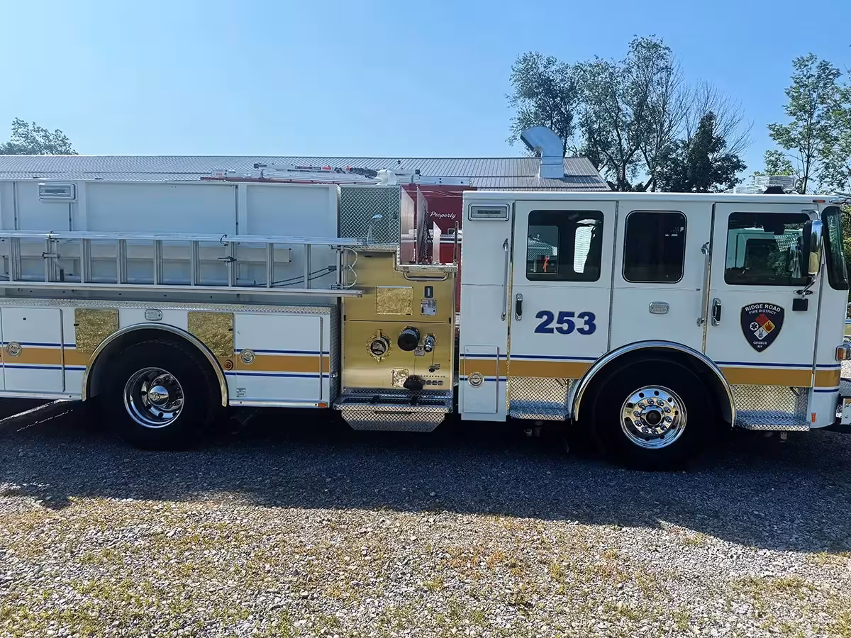 Pumper driver-side profile view showing pump panel, side compartments, and roof ladder