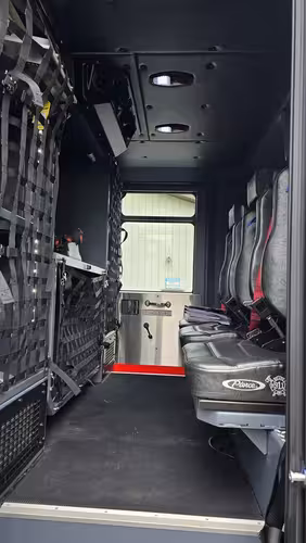 Rear crew compartment view showing bench seats, SCBA seat mounts, and hosebed netting