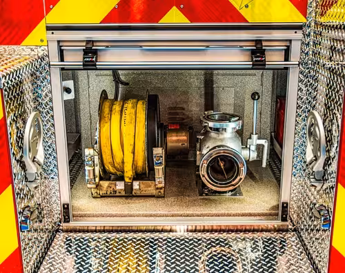 Rear compartment close-up showing coiled hose, large intake port, and compartment trim