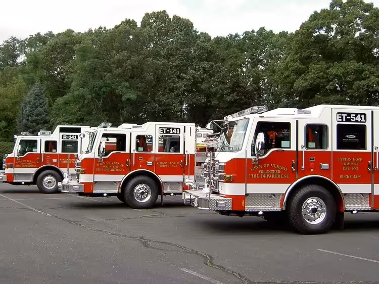 Pumper lineup side view showing multiple red-and-white apparatus parked in lot