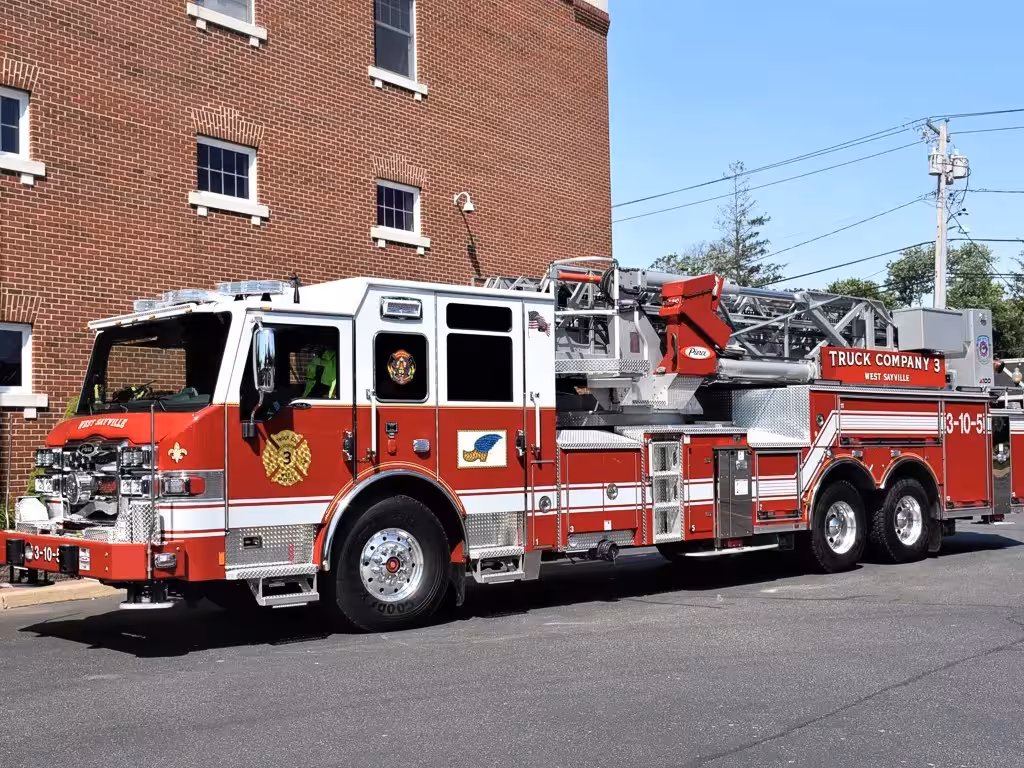 Tower ladder truck front-left exterior view parked by brick building
