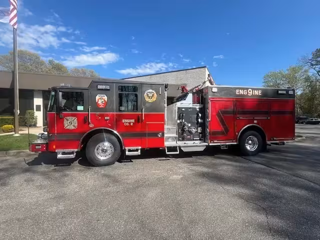 Pierce Enforcer top-mount pumper, driver-side profile view showing pump panel and side compartments