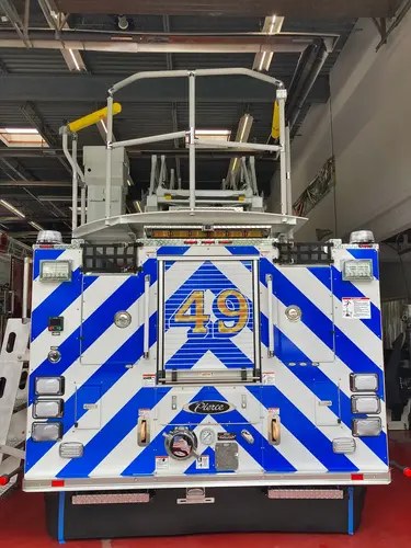 Rear view with elevated bucket showing chevron striping and rear discharges