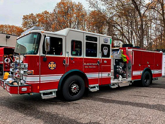 Pumper-tanker front-left exterior view showing enclosed cab, pump panel area, and side compartments