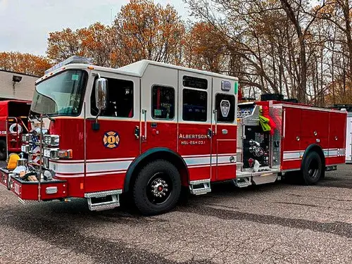 Pumper-tanker front-left exterior view showing enclosed cab, pump panel area, and side compartments