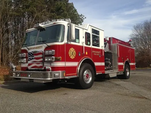 Front-right exterior view of a pumper showing the cab, bumper, pump panel section, and side body.