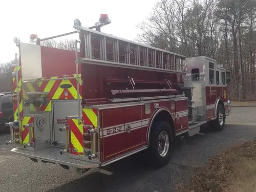 Rear-left exterior view showing side ladder rack, rear chevron panel, and hosebed area.