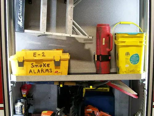 Open side compartment showing bins, ladder sections, and cooler storage