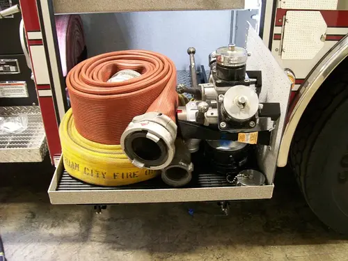 Open side compartment showing rolled hose and pump-side fittings