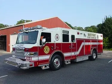 Front left exterior view of a rescue truck with chrome bumper, crew cab, and long side body compartments.