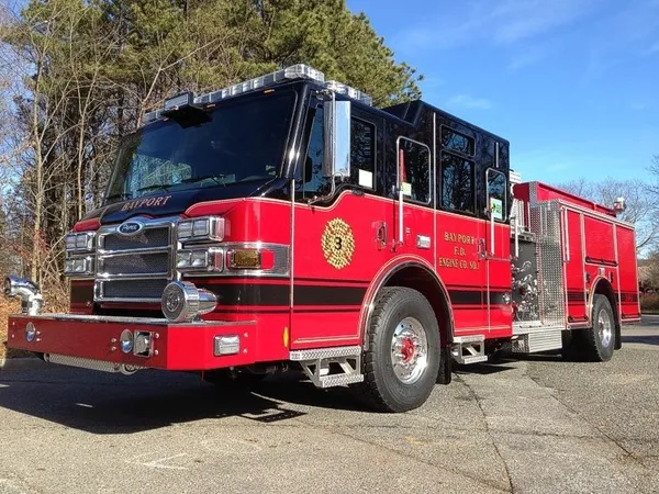 Front-left exterior view of a pumper showing the enclosed cab, pump panel section, and rear body compartments.