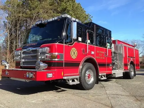 Front-left exterior view of a pumper showing the enclosed cab, pump panel section, and rear body compartments.