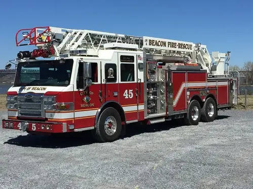 Front left exterior view of a rear-mount aerial ladder truck with tandem rear axles and stowed ladder.