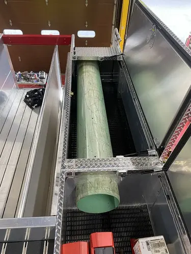 Open upper side compartment showing long cylindrical tube in narrow storage channel