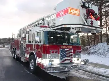 Tower ladder truck front-left exterior view showing raised bucket and cab