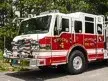 Wide front-right view of the pumper parked roadside with cab and side body visible.