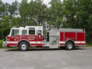 Driver-side full profile showing pump panel section, side compartments, and wheel/tire area.