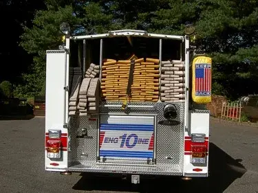 Rear view showing open hosebed with stacked hose and rear warning lights