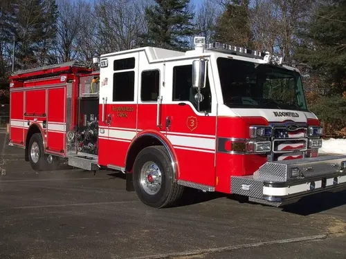 Front right exterior view of a red-and-white pumper with chrome bumper, crew cab, and side compartments.