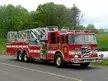 Wide front right view of the parked mid-mount tower ladder with full apparatus length visible.