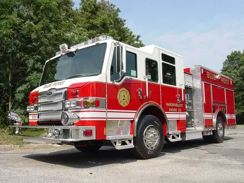 Front-right exterior view of a pumper showing the cab, bumper, pump panel section, and side compartments.