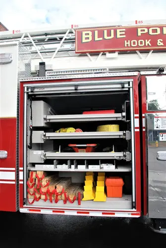 Open side compartment showing nozzles and hand tools on shelves