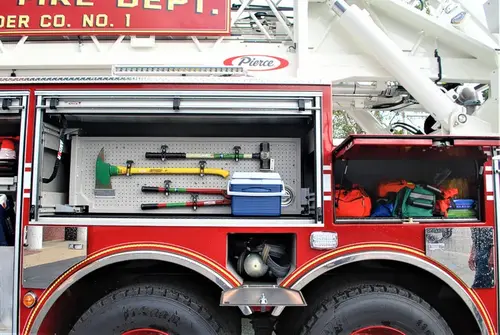 Open side compartment showing mounted tools and shelf storage by tandem wheels