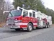 Wide front-left thumbnail view of the tower ladder parked roadside.