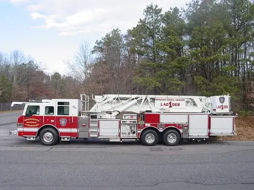 Driver-side full profile showing stowed aerial ladder sections, side compartments, and tandem wheelbase.