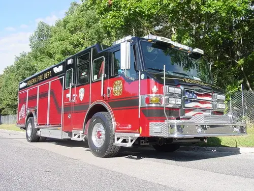 Front-right exterior view of a heavy rescue truck with enclosed cab, side compartments, and wheel/tire area.