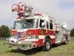 Aerial ladder truck front-left exterior view showing enclosed cab and ladder sections