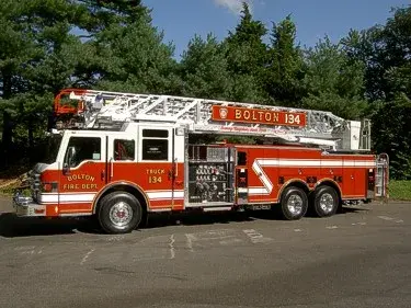 Driver-side full profile showing ladder bed, pump panel, and tandem rear axles