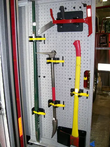 Open narrow compartment showing mounted hand tools in vertical slots