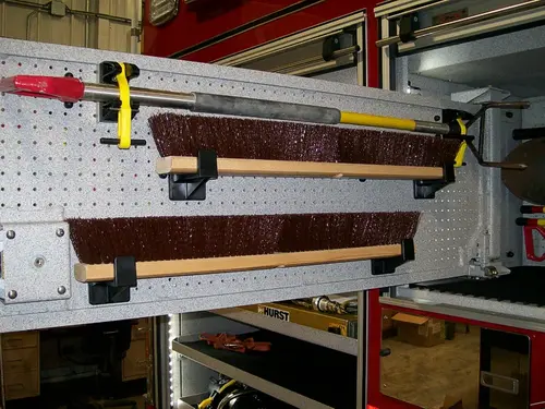 Open side compartment showing shelf-mounted long tools and brackets